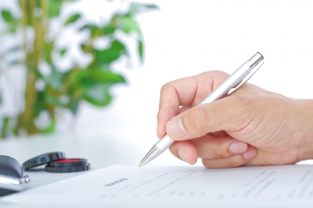 ペンを持つ手と書類